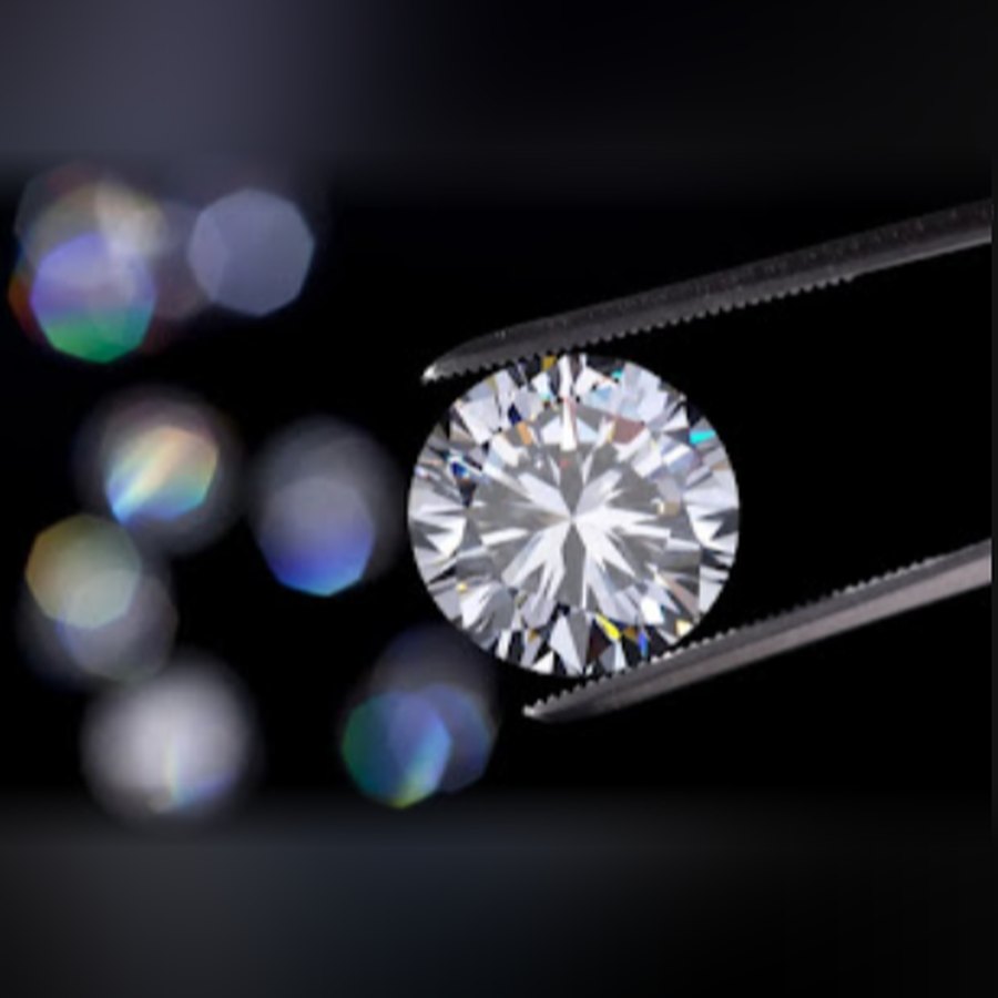 Round brilliant diamond held in tweezers