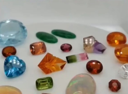 Loose gemstones from our inventory: blue topaz, emerald cabochons, garnet, citrine, fire opal, bi-color tourmaline, peridot, amethyst and opal