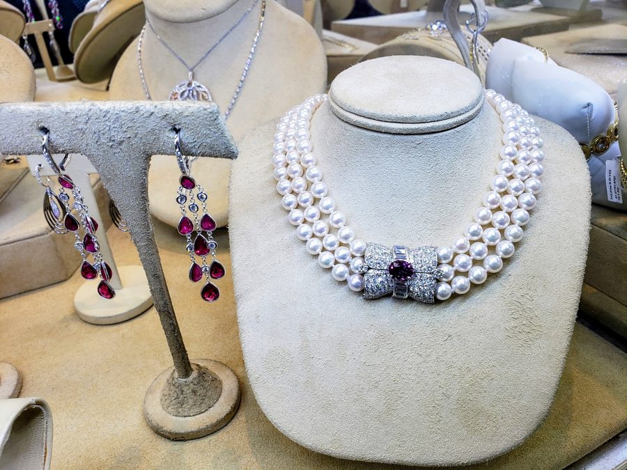 MM Fine Jewelry and Gems pieces on display at Solomons Jewelers: three-strand Akoya pearl necklace with ruby and diamond clasp, and ruby drop earrings