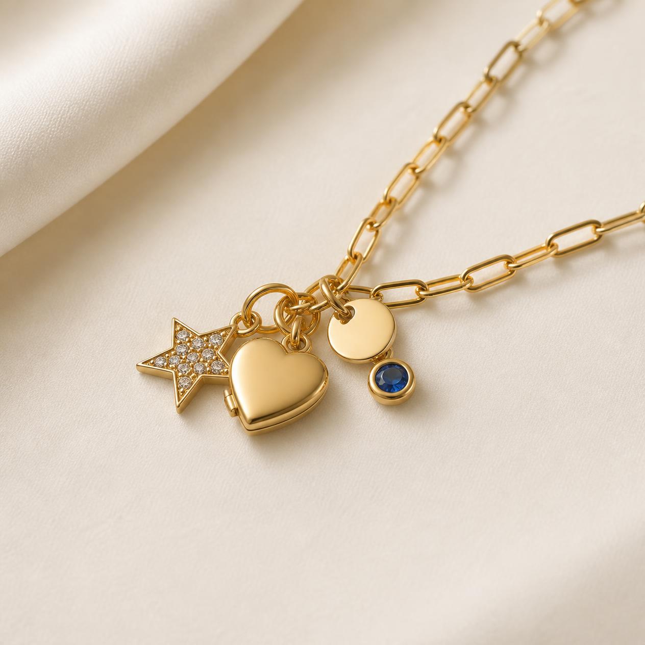Gold paperclip chain with a diamond star, heart locket, initial disc and sapphire charm