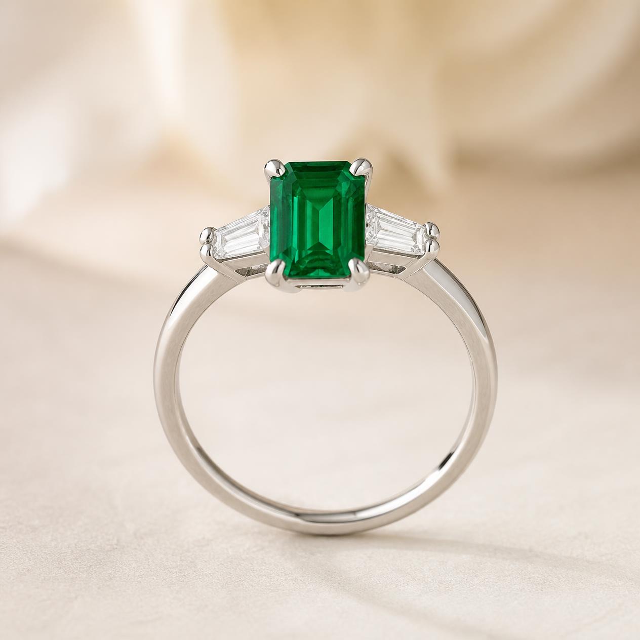 Emerald-cut green emerald with tapered baguette diamonds in platinum