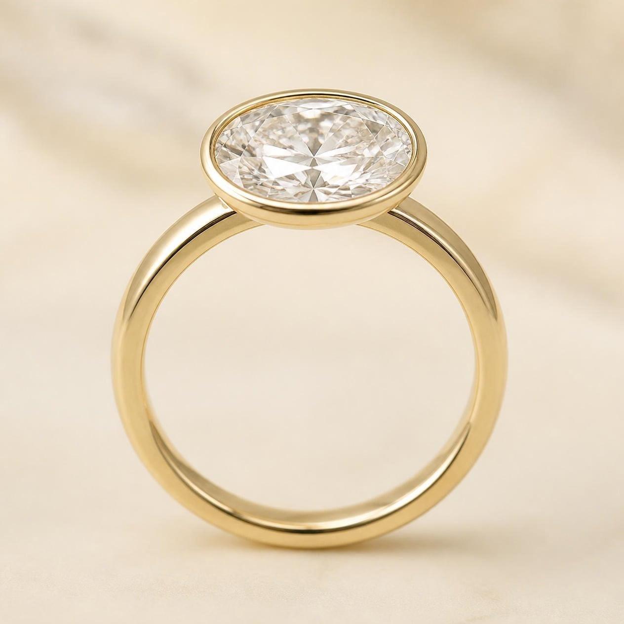 Oval diamond set east-west in a slim yellow gold bezel