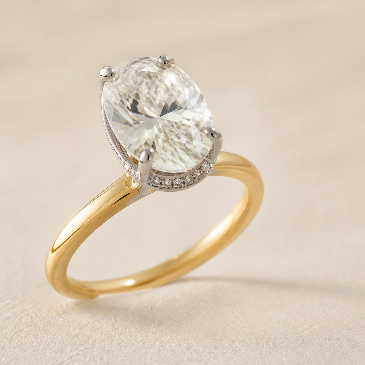 Oval diamond on a yellow gold band with a platinum head and hidden halo