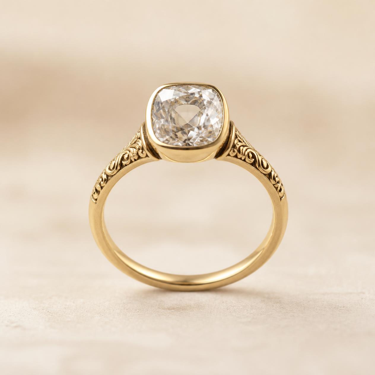 Old mine cushion-cut diamond in a yellow gold bezel with hand-engraved shoulders